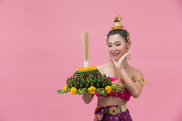 Loy Krathong Festival. Frau im thailändischen traditionellen Outfit hält dekorierten Auftrieb