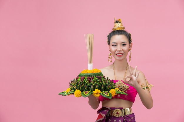 Loy Krathong Festival. Frau im thailändischen traditionellen Outfit hält dekorierten Auftrieb