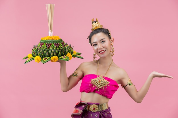 Kostenloses Foto loy krathong festival. frau im thailändischen traditionellen outfit hält dekorierten auftrieb