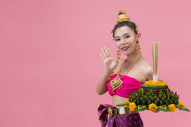 Loy Krathong Festival. Frau im thailändischen traditionellen Outfit hält dekorierten Auftrieb