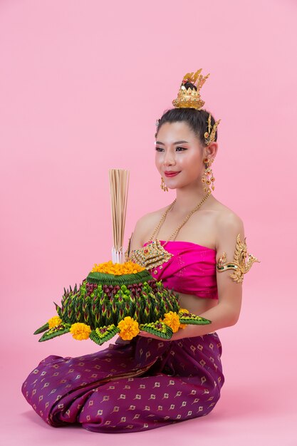 Loy Krathong Festival. Frau im thailändischen traditionellen Outfit hält dekorierten Auftrieb