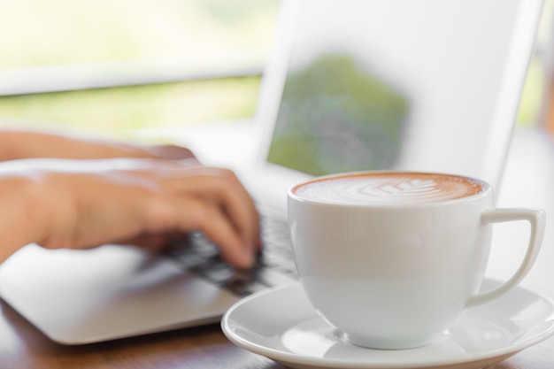 Lperson arbeitet an einem Laptop mit einer Tasse Kaffee neben