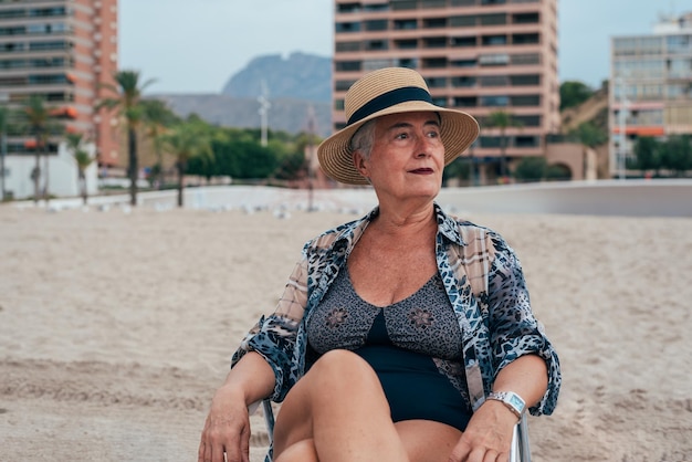 Ältere Frau am Strand trägt einen Strohhut