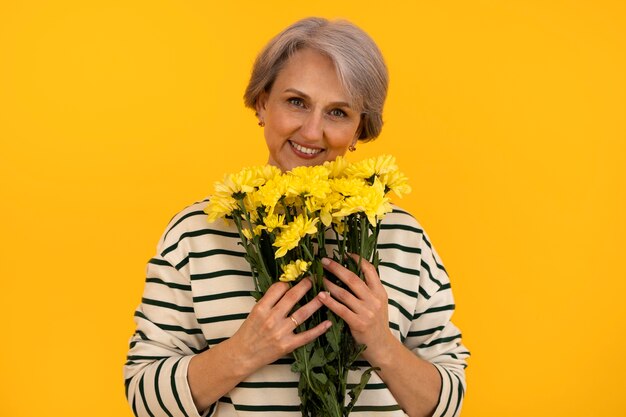 Ältere Frau der Vorderansicht, die mit Blumen aufwirft