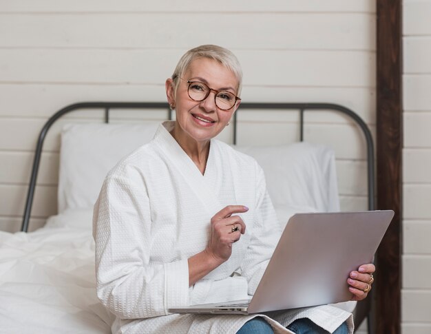 Ältere Frau des modernen smiley, die einen Laptop verwendet