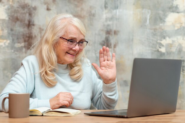 Ältere Frau des niedrigen Winkels, die an Laptop arbeitet