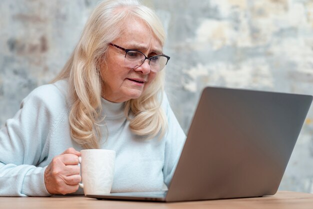 Ältere Frau des niedrigen Winkels, die Laptop verwendet