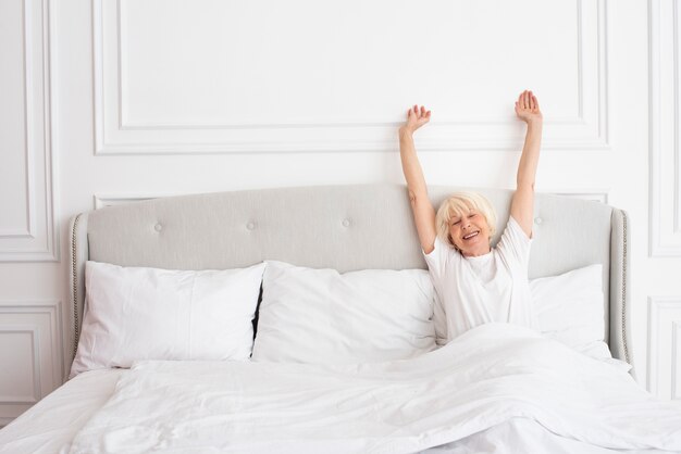 Ältere Frau des smiley, die in das Schlafzimmer legt