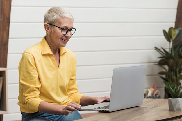 Ältere Frau, die durch das Internet auf ihrem Laptop schaut