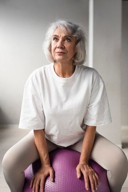 Ältere Frau, die ein Gymnastikballtraining im Fitnessstudio macht