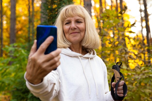 Ältere Frau, die ein Selfie beim Wandern in der Natur nimmt