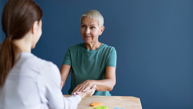 Ältere Frau, die eine Ergotherapiesitzung mit einem Psychologen mit Kopienraum macht