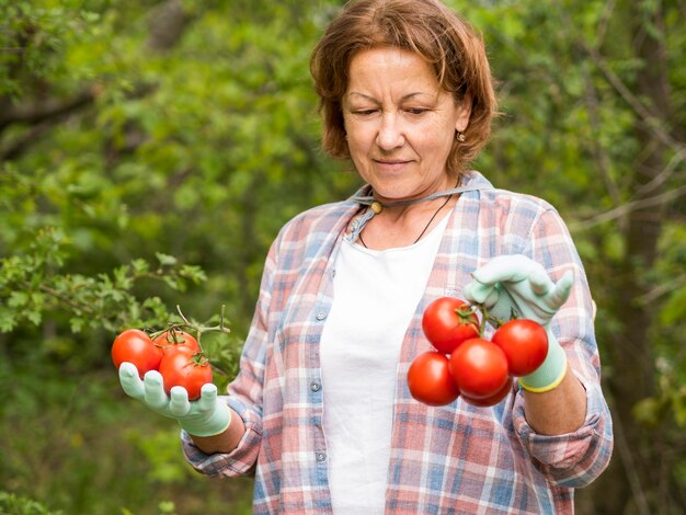 Ältere Frau, die einen Bündel Tomaten hält