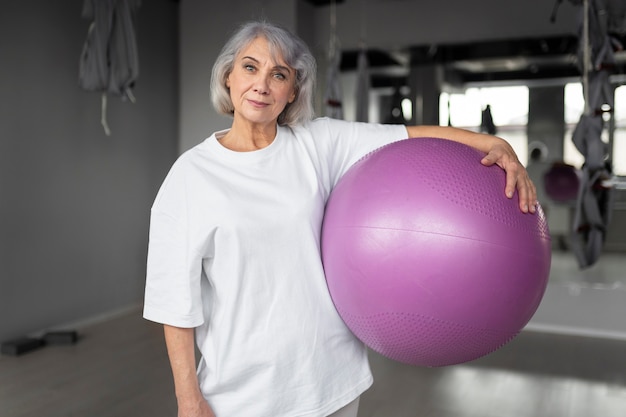 Ältere Frau, die Gymnastikballübungen im Fitnessstudio macht