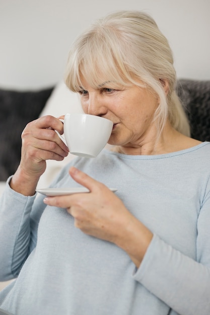 Ältere Frau, die heißes Getränk genießt