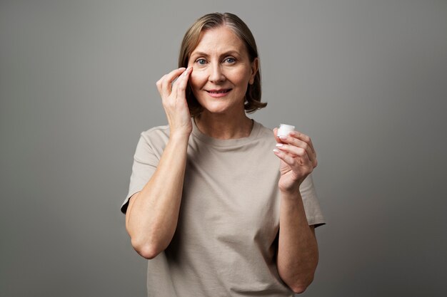 Ältere Frau, die mittlere Aufnahme der Gesichtscreme verwendet