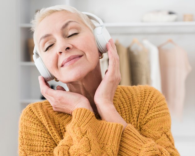 Ältere Frau, die Musik auf Kopfhörern genießt