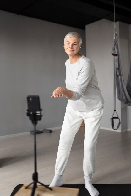 Ältere Frau, die sich bei Fitnessübungen im Fitnessstudio filmt