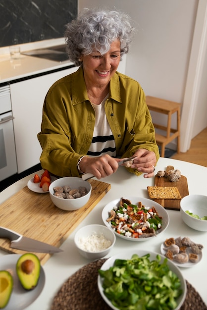 Ältere Frau, die Teller mit Feigen in der Küche macht