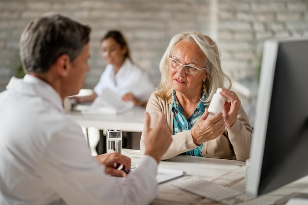 Ältere Frau, die während der Konsultationen in der Klinik mit ihrem Arzt über ihre verschreibungspflichtigen Medikamente spricht