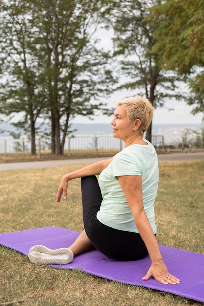 Ältere Frau, die Yoga draußen im Park tut