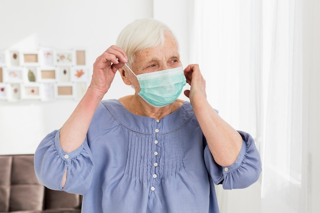Ältere Frau, die zu Hause medizinische Maske trägt