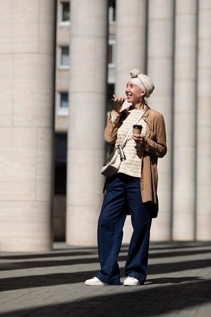 Ältere Frau draußen in der Stadt, die beim Kaffee telefonieren