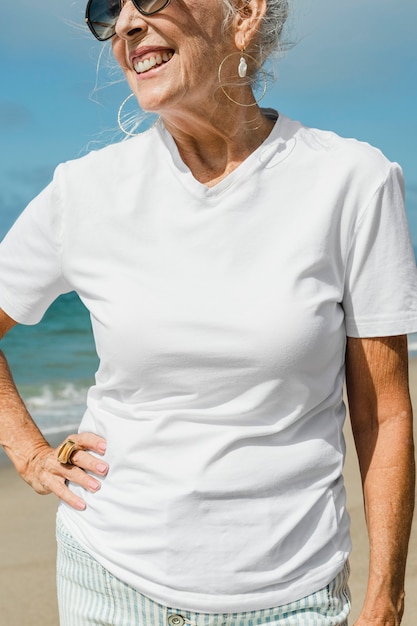 Ältere Frau im weißen T-Shirt am Strand