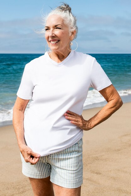 Ältere Frau im weißen T-Shirt am Strand