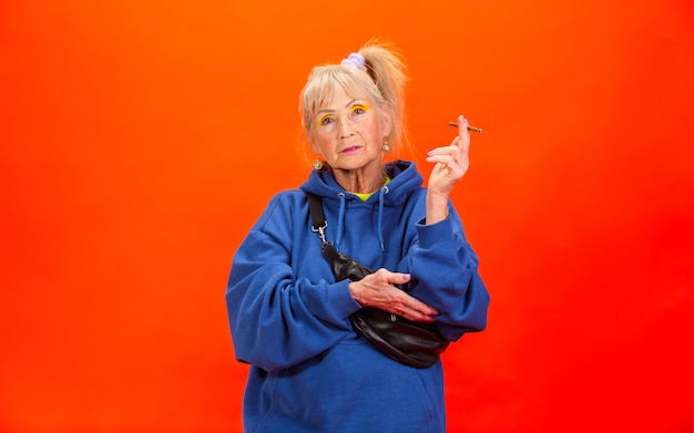Ältere Frau in ultra trendiger Kleidung isoliert auf Orange
