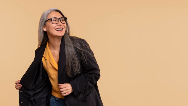 Ältere Frau lächelt und trägt eine Brille vor gelbem Hintergrund