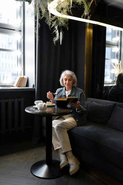 Ältere Frau liest ein Buch und trinkt Kaffee in einem Café