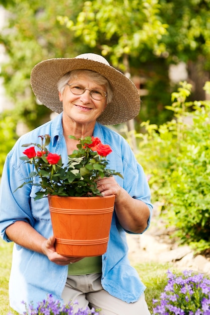 Ältere Frau mit Blumen im Garten