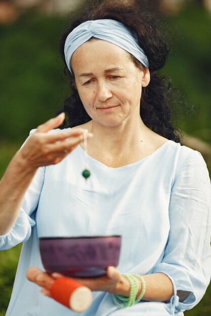 Ältere Frau mit hinduistischen Dingen. Dame in einem blauen Kleid. Brünette sitzt.