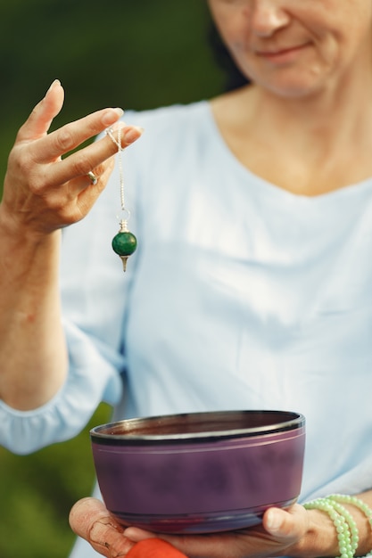 Ältere Frau mit hinduistischen Dingen. Dame in einem blauen Kleid. Brünette sitzt.