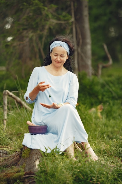 Ältere Frau mit hinduistischen Dingen. Dame in einem blauen Kleid. Brünette sitzt.