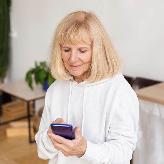 Ältere Frau mit Smartphone zu Hause