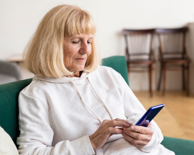 Ältere Frau mit Smartphone zu Hause