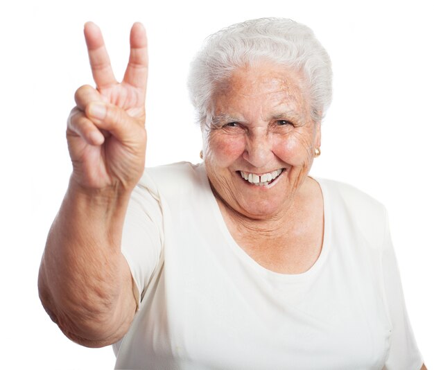 Ältere Frau mit zwei Fingern hob lächelnd
