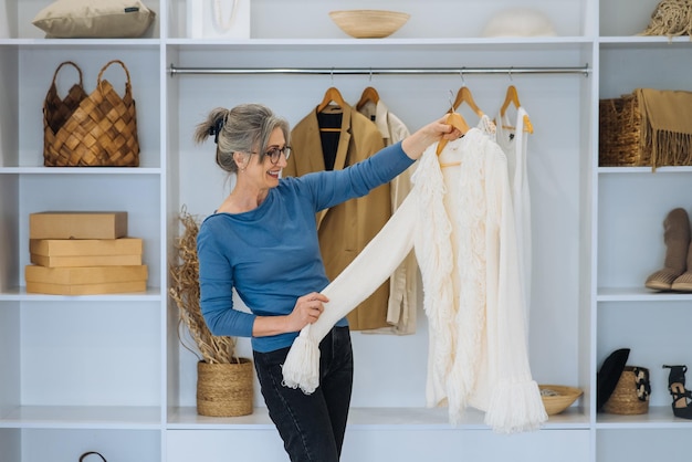 Ältere Frau wählt zu Hause einen weißen Pullover