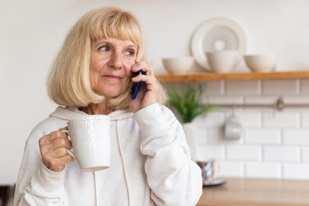 Ältere Frau zu Hause am Telefon beim Kaffee sprechen
