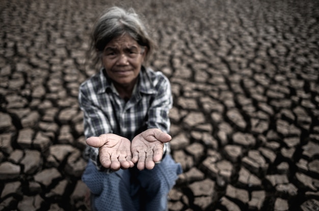 Ältere Frauen machen Hände, um Regenwasser bei trockenem Wetter, globaler Erwärmung, vorgewählter Fokus zu erhalten.