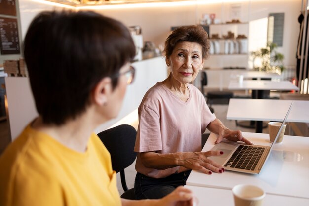 Ältere Frauen verbringen Zeit zusammen in einem Café, arbeiten und trinken Kaffee