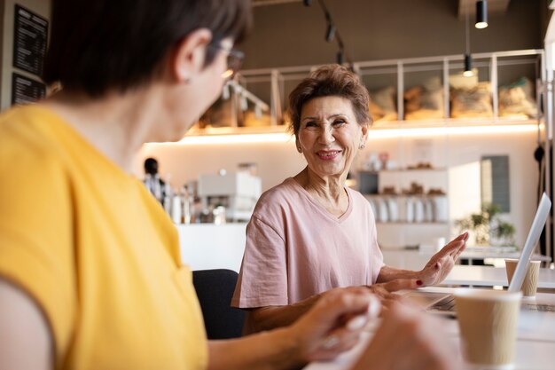 Ältere Frauen verbringen Zeit zusammen in einem Café, arbeiten und trinken Kaffee