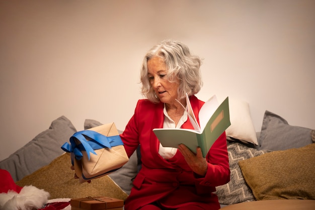 Ältere glückliche Frau, die Buch und Geschenk hält
