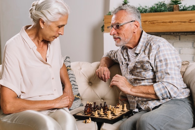 Ältere Paare, die auf dem Sofa spielt Schach sitzen