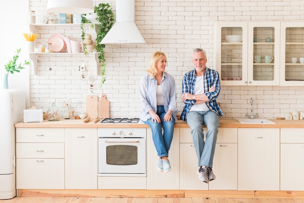 Ältere Paare, die auf Küchenarbeitsplatte sitzen