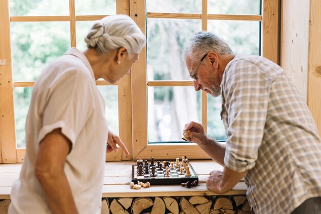 Ältere Paare, die Schach auf Fensterbrett spielen