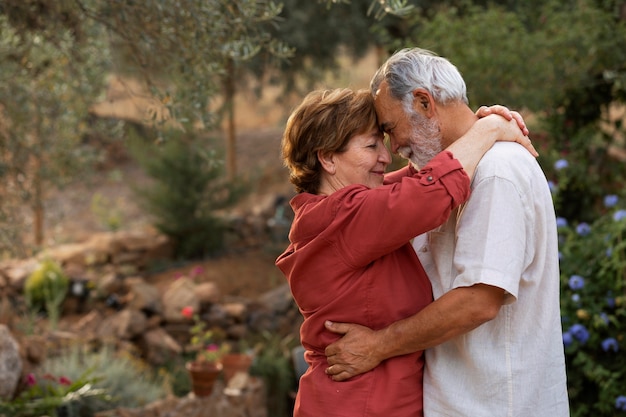 Ältere Paare, die sich romantisch in ihrem ländlichen Hausgarten halten