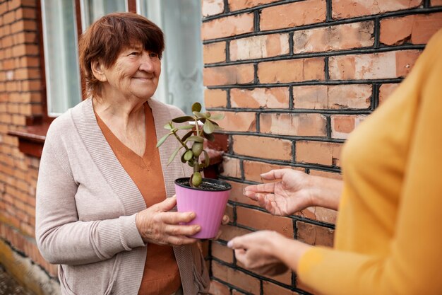 Ältere Person, die Neoghbor ein Geschenk anbietet